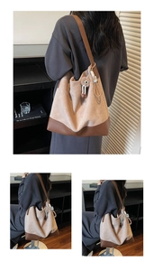 Detail of large beige suede tote bag with brown leather trim and fuzzy monster charm