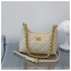 Detail of cream quilted crossbody bag with gold twist lock and chain strap on shelf