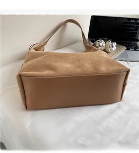 Close-up of soft brown suede texture and smooth leather base of the shoulder bag