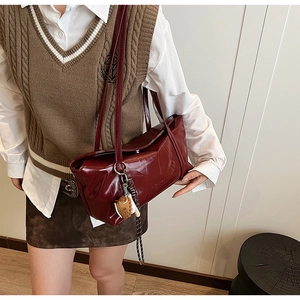Detail of burgundy PU leather shoulder bag with fish pendant and woven lanyard detail