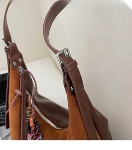 Close-up of premium silver-tone metal hardware and leather strap on a brown suede bag