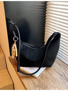Minimalistische schwarze Wildleder-Hobo-Tasche mit Leoparden-Holzperlen-Anhänger auf Stufen