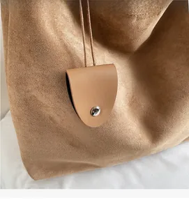 Close-up of brown suede tote bag featuring a matching round coin purse with silver buckle