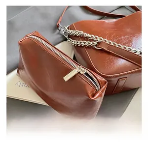 Detail view of premium brown leather texture with silver hardware and chain on bucket bag