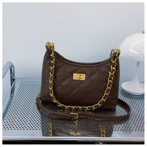 Detailed view of brown quilted bag with gold chain strap and metallic twist lock on surface