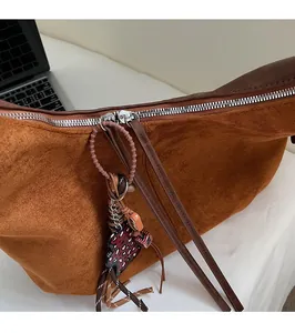 Detail of brown suede bag featuring silver metal zipper with leather puller and leopard charm