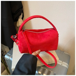 Dettaglio della borsa a cilindro in pelle rossa smerigliata con tracolla e metallo