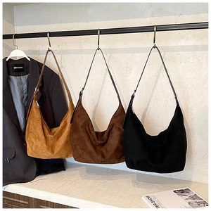 Detail of suede hobo bags in caramel, dark coffee, and black with metal strap buckle