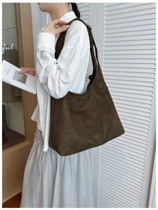 Detail view of olive green matte suede tote bag with wide shoulder strap on model