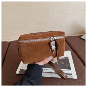 Detail of brown suede crossbody bag featuring a silver robot zipper charm and wrist strap