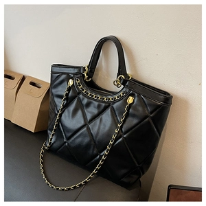 Détail d'un sac cabas noir matelassé avec bandoulière en chaîne dorée et cuir PU durable