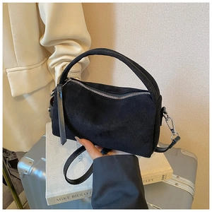 Dettaglio della texture in pelle scamosciata opaca nera e zip argentata della borsa mini