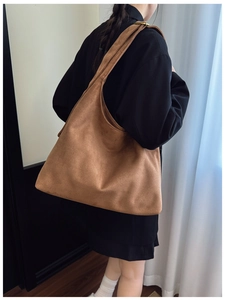 Detail view of brown faux suede tote bag with metal buckle on the shoulder strap