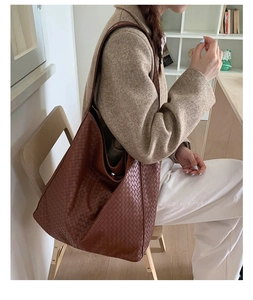 Close-up of a model wearing a brown woven leather hobo shoulder bag in a library setting
