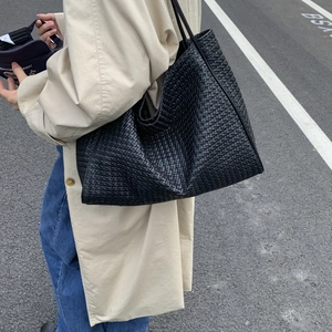 Vue détaillée du sac cabas tissé noir avec texture précise et fines bretelles d'épaule