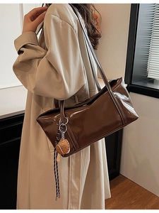 Brown patent leather tote bag with shoulder strap and stylish sneaker charm pendant