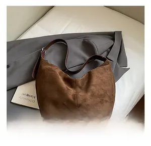 Detail showing deep brown suede hobo bag with leather strap on grey blazer