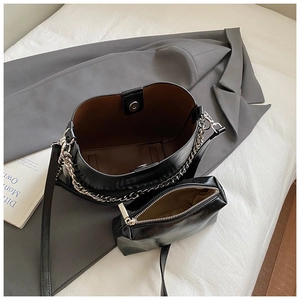 Detail view of black glossy bucket bag with interior small pouch and silver chain strap