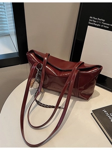 Deep red patent leather tote bag with glossy finish and sporty baseball charm for daily commute