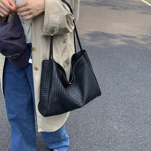 Gros plan d'un sac cabas tissé noir avec doubles bandoulières dans un cadre extérieur