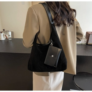 Detail of a black suede tote bag with small buckle pouch shown on a person shoulder