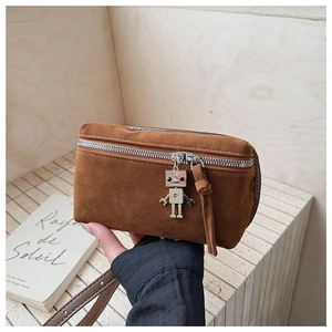 Detail of brown suede crossbody bag showing silver zipper and robot metal pendant