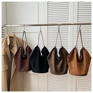 Detail of minimalist suede tote bags in four autumn colors hanging in a dressing room
