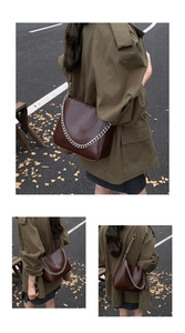 Close-up of vintage dark brown bucket bag with silver chain and glossy finish texture