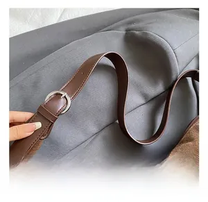 Detail view of the brown suede bag featuring an adjustable dark brown leather strap