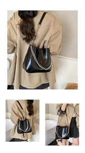 Detail showing high-gloss black bucket bag with silver metal chain and adjustable strap