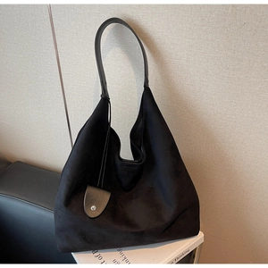 Close-up of black suede hobo bag with a silver metal buckle and leather strap detail