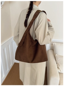 Close-up of dark brown suede tote bag with adjustable gold hardware and wide shoulder strap