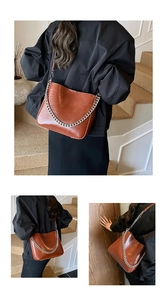 Detail of vintage brown shoulder bag featuring a chunky silver chain and glossy finish