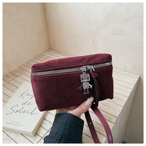 Close-up of burgundy suede crossbody bag featuring a unique silver robot metal charm detail