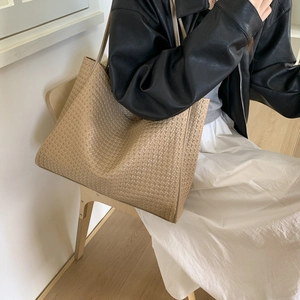Sac fourre-tout en cuir tressé beige au design minimaliste porté à l'épaule chic