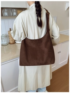 Close-up of brown suede hobo bag with adjustable wide strap shown in a lifestyle setting