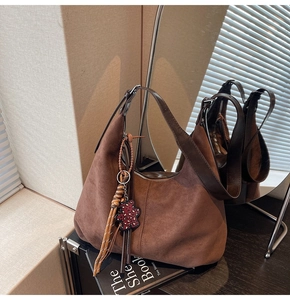 Detail of brown faux suede hobo bag with braided tassels and leopard bear charm