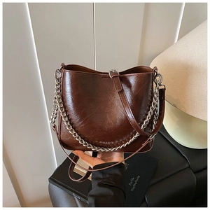 Detail of vintage brown glossy leather bucket bag with silver chain and logo engraving