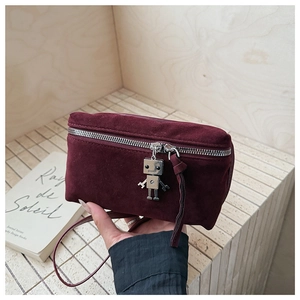 Close-up of burgundy suede crossbody bag featuring a silver robot pendant and metal zipper