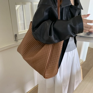 Gros plan d'un sac cabas marron tissé montrant la texture et la capacité sur un modèle