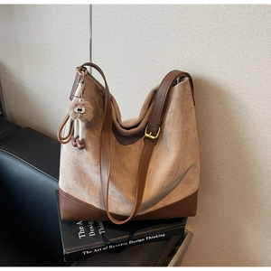 Close-up of khaki suede tote bag with brown leather details and a cute doll charm