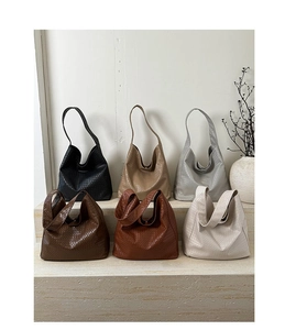 Collection of woven underarm tote bags in six different colors on a minimal display