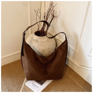 Detail of dark brown faux suede hobo bag with adjustable strap in a warm interior setting