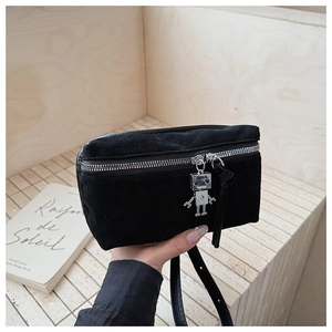 Close-up of black suede bag with silver robot pendant and metallic zipper detail
