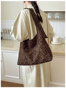 Model wearing a large leopard print hobo bag with a wide strap in a minimalist setting