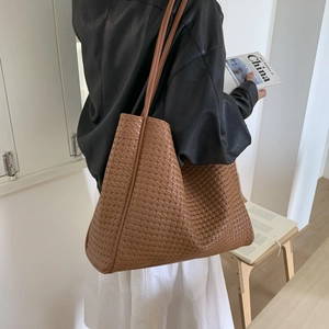 Détail rapproché de la texture en cuir tressé d'un grand sac cabas marron pour femme
