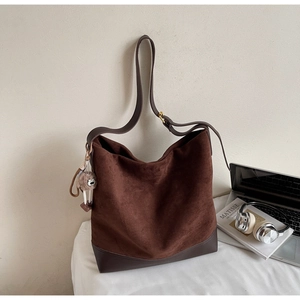 Detail of coffee suede tote bag with owl pompom charm and brown leather bottom