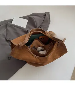 Detail view of large brown suede tote bag showing spacious interior with zipper pouch