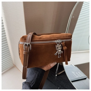 Detail of a brown suede crossbody bag featuring a unique silver robot zipper charm