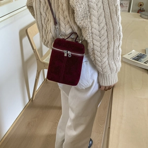 Modische weinrote Wildleder-Eimertasche in einem warmen Indoor-Lifestyle-Ambiente